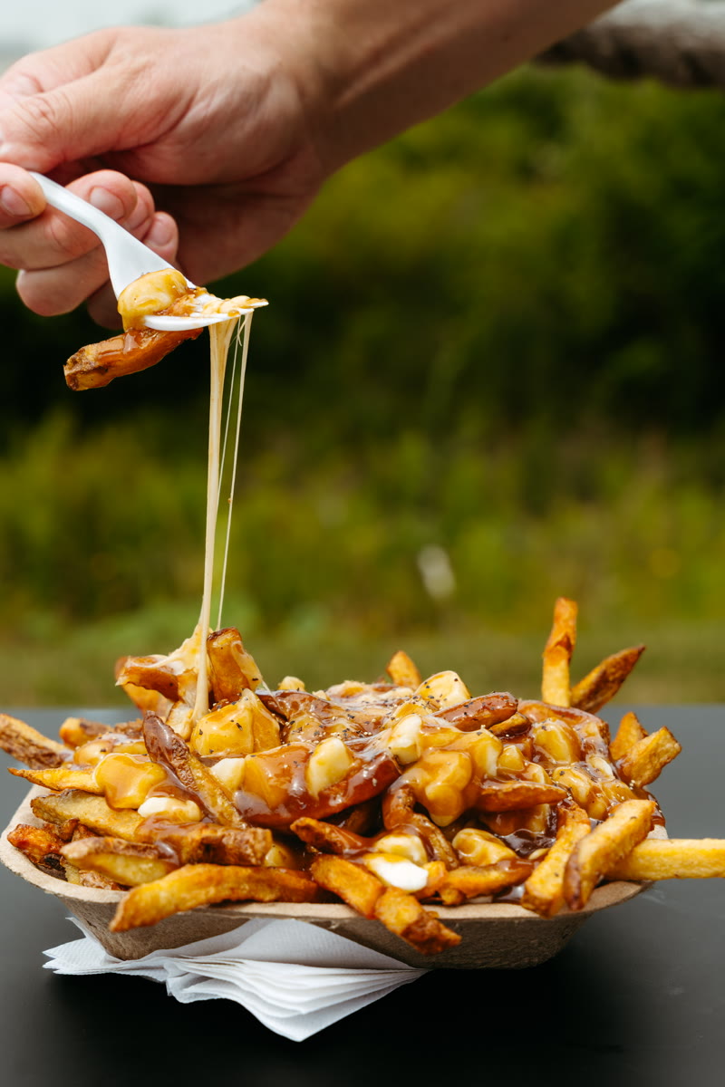 A fork lifting a cheese pull from Bud the Spud poutine